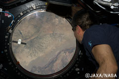 ようやく打ち上げられ接近するドラゴン宇宙船を、ISSの窓から見つめる若田飛行士。（提供：JAXA/NASA）