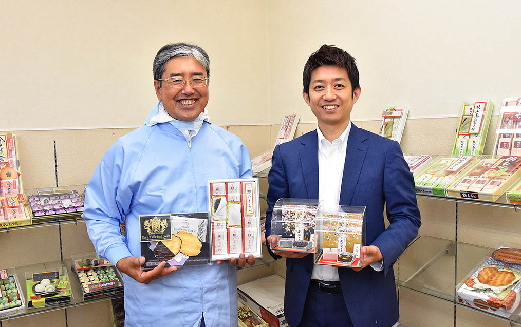竹内製菓グループの製品を持つ清水氏（右）と荒井氏（左）