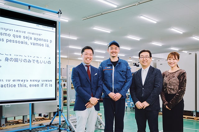 翻訳サイネージと稲垣さん、大竹さん、松原さん、岡村さんの写真