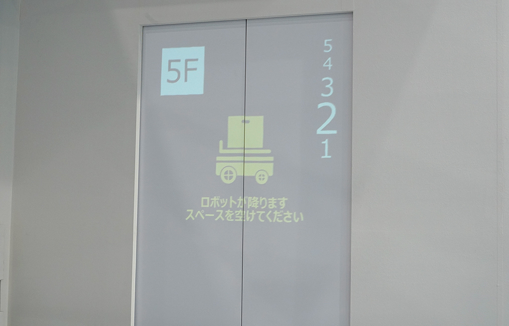 エレベーターの扉にロボットの到着を知らせるサインが表示される画像1