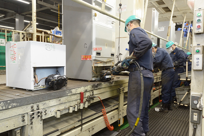 冷蔵庫を立てた状態でフロンを回収する作業の写真