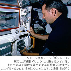 シャトルのキッチン「ギャレー」。飛行士が粉末ドリンクにお湯を注いでいる。上のつまみで温度を調節できるが最高70度まで。ここでラーメンにお湯を注ぐことになる。（提供：NASA）