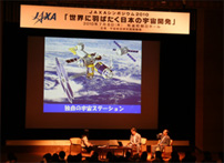 シンポジウムで紹介された「日本独自の宇宙ステーション」（イメージ）。HTVや「きぼう」の技術で実現できるのだとか。「足りないのはお金ぐらいです」と虎野プロマネ（右端）