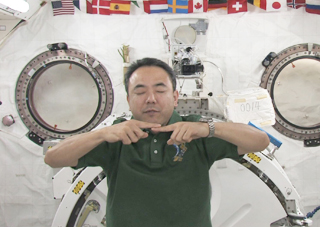 宇宙医学にチャレンジ！実験で。目をつぶると指と指が合わない・・。同実験では足の裏の皮（角質）が剥がれる様子も披露し、「身体を張る」古川さん。（提供：JAXA）