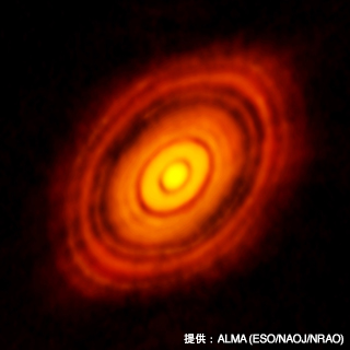アルマ望遠鏡が視力2000でとらえた惑星誕生の現場写真。おうし座の方向約450光年にあるおうし座HL星の周りにあるチリの円盤。惑星が誕生するときは円盤の中のチリやガスをかき集めて成長していくため、溝ができると考えられている。理論通りの溝が複数、撮影された画期的な画像だ。（提供：ALMA(ESO/NAOJ/NRAO) ）