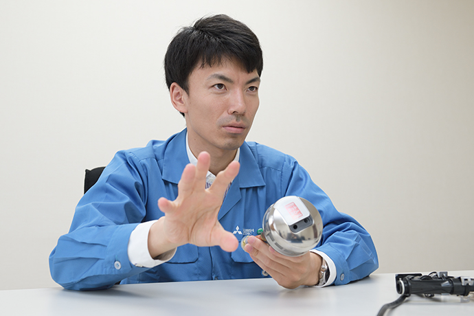 「ホットあわー」のアダプターを手にとり説明する松村さん